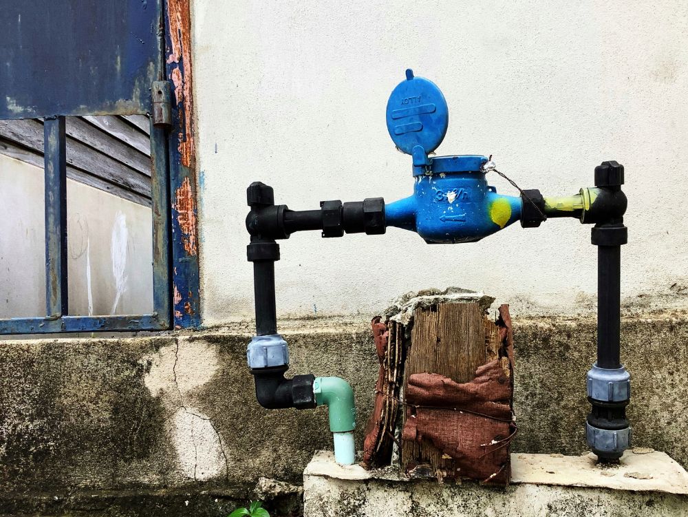 Hidrômetro e tubulação externa instalados na parede; situação comum quando a pessoa pensa “minha conta de água veio um absurdo” e suspeita de vazamento oculto.